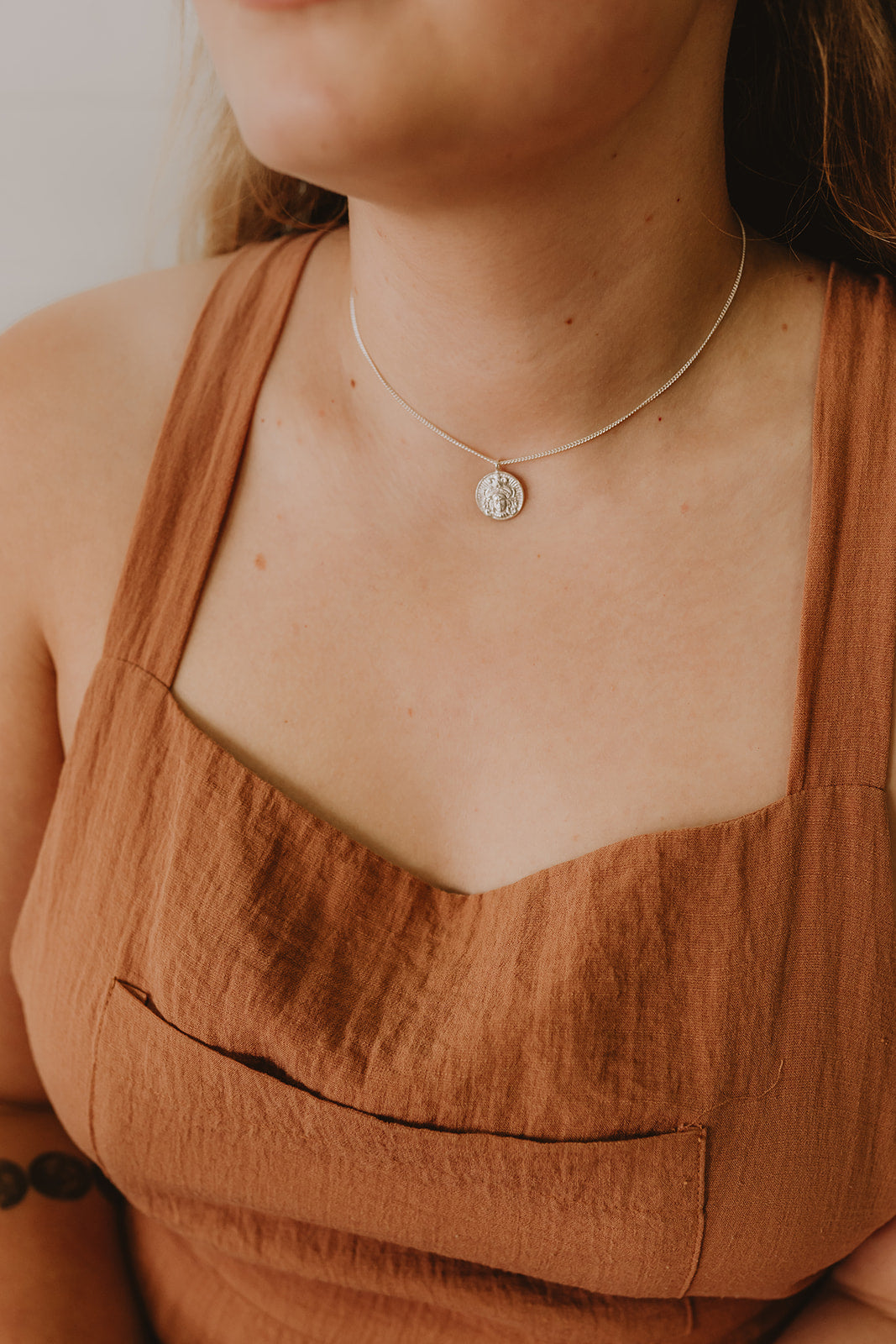 Silver necklace with Kali stamped into coin pendant on model.