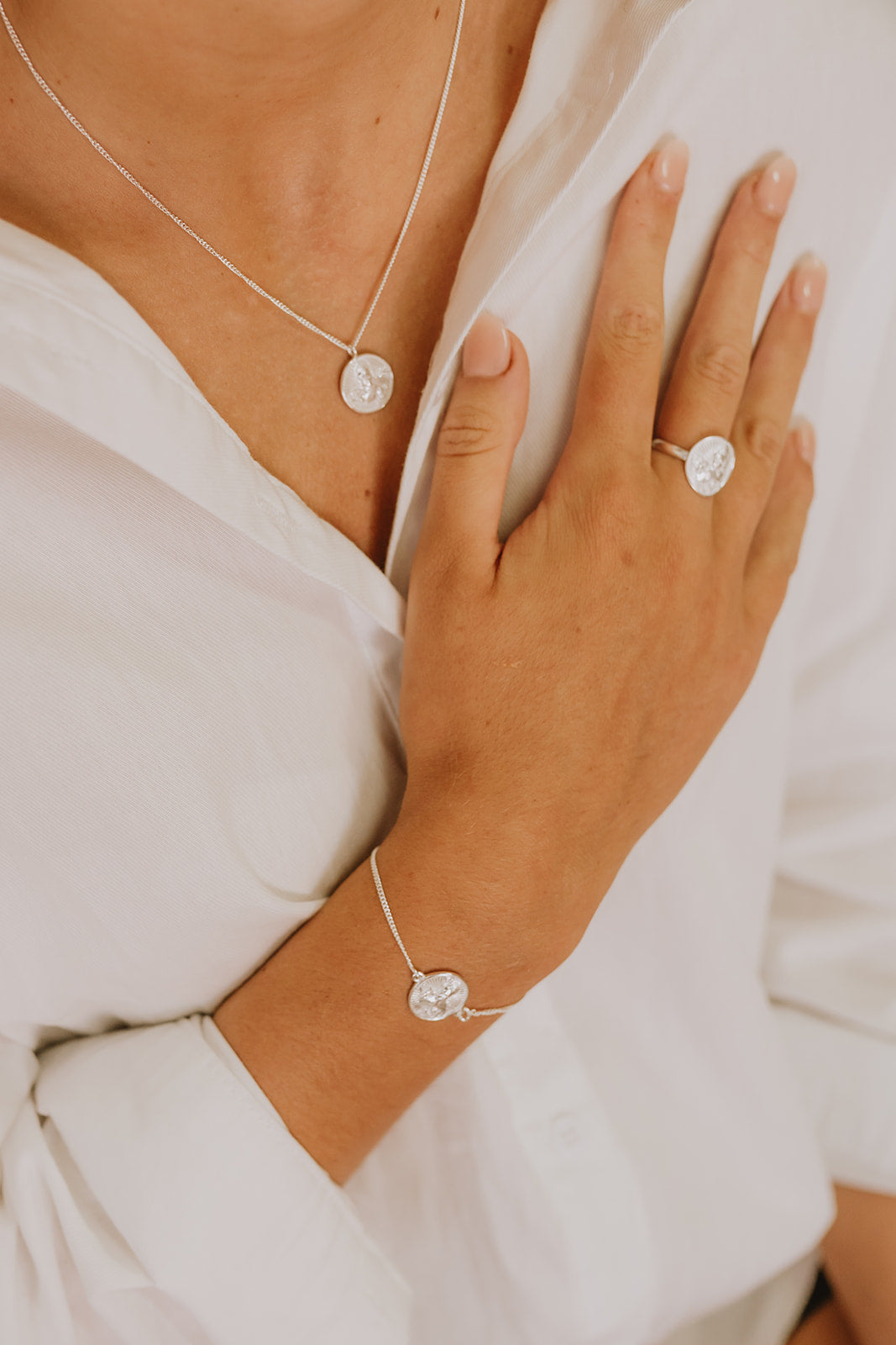 Delicate silver bracelet with Lakshmi stamped into coin pendant on model.
