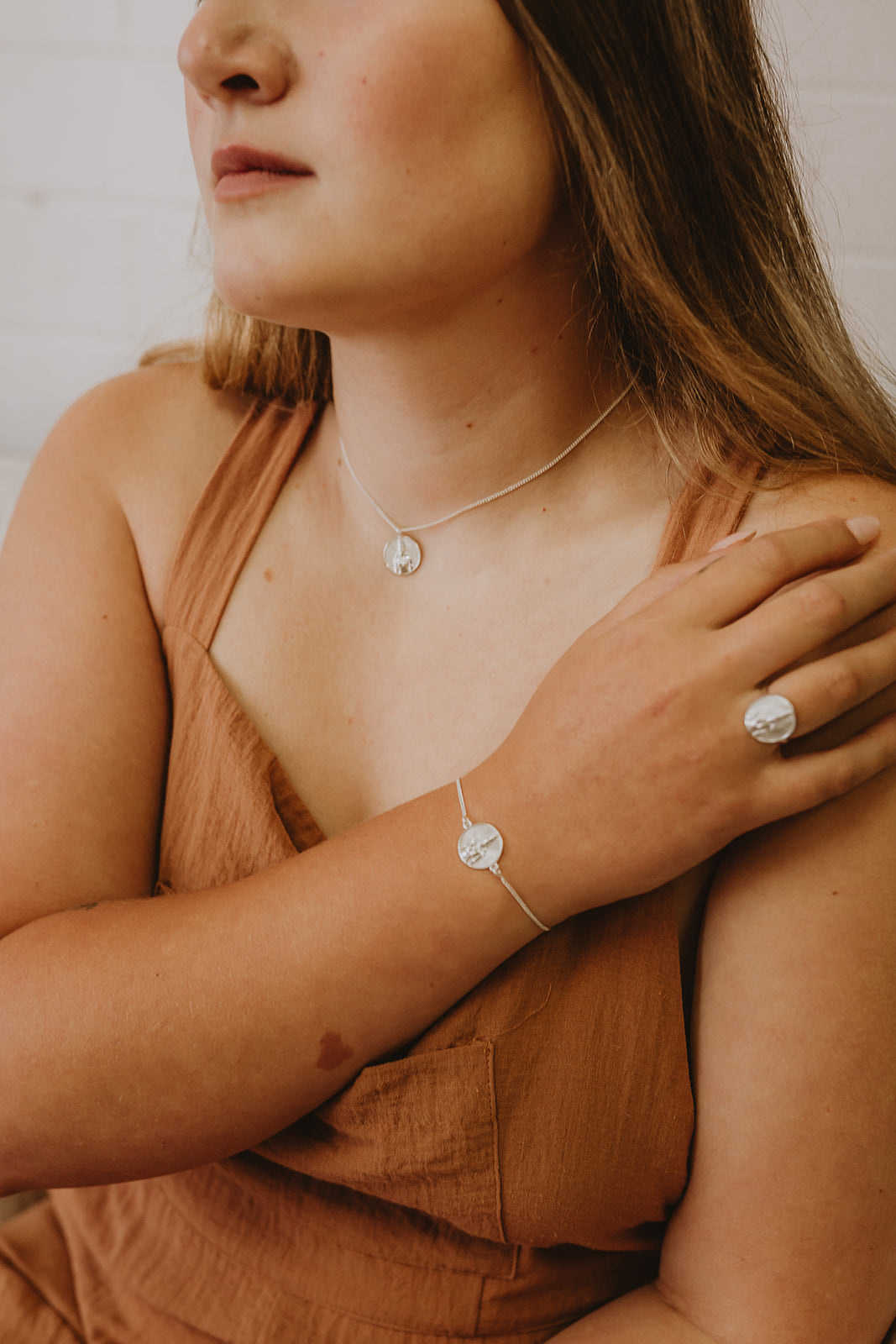 Delicate silver bracelet with Rati stamped into circle pendant on model.