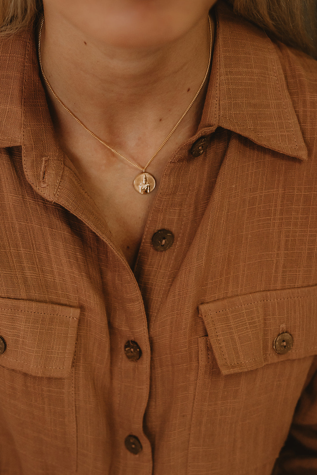 Gold necklace with Rati stamped into coin pendant on model.