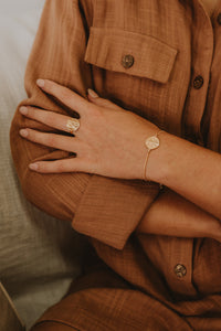 Delicate gold ring with Rati stamped into circle on model.